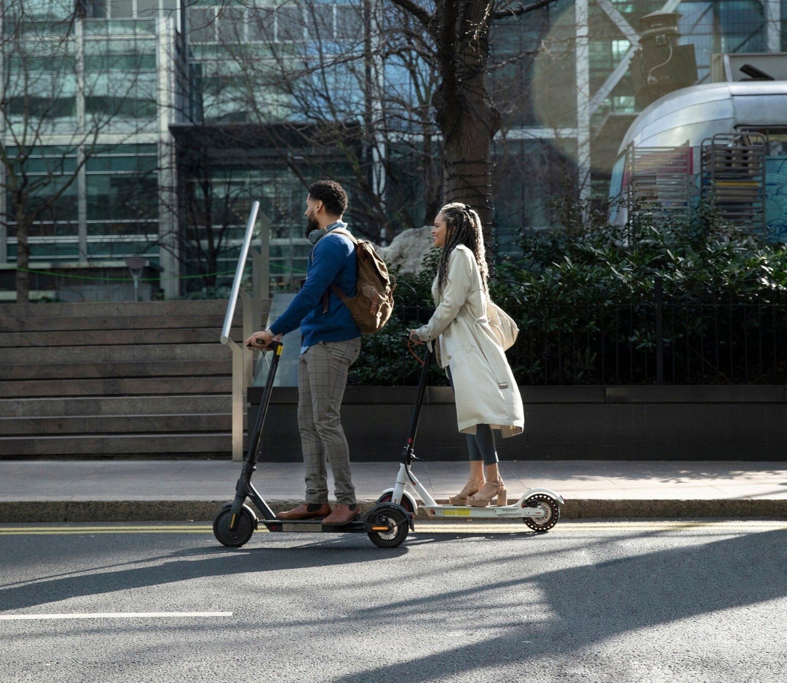 two people on scooters going down the street